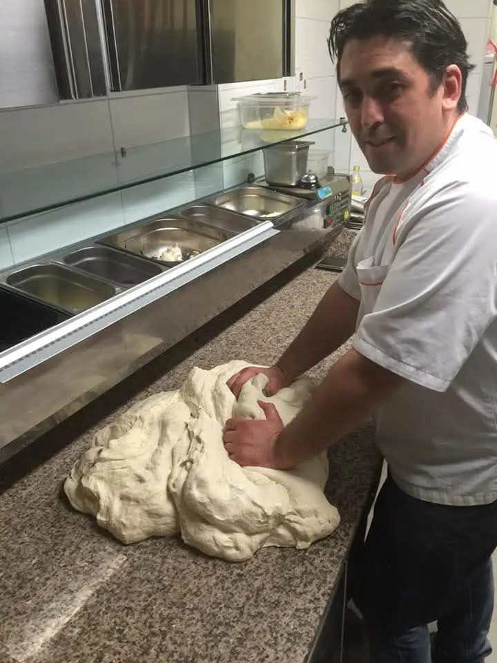 Luca knetet in der Küche frischen Pizzateig von Hand